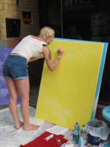 artist Sally Brown drawing on yellow canvas