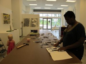 a woman working in a gallery, a toddler walking