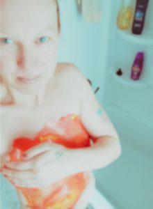 Caucasian woman with orange paint on her body getting in shower