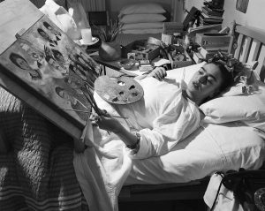 an artist painting in bed